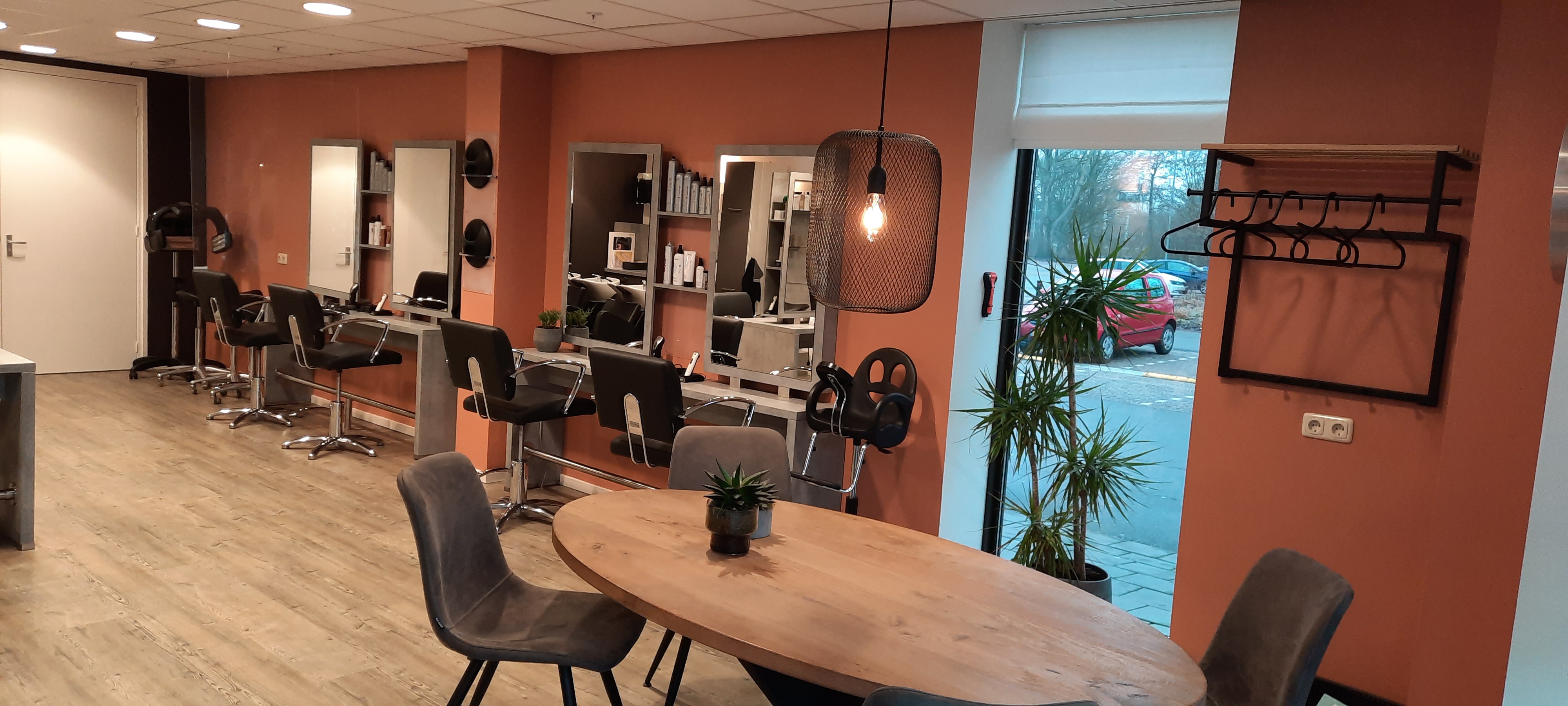Ruim overzicht van de lichte salon met kappersstoelen